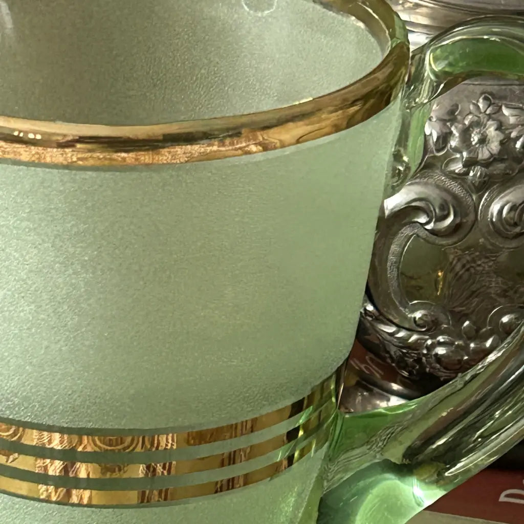 Green glass mug with gold accents and a decorative handle